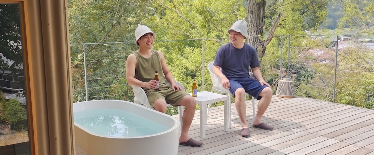 サウナ上がりにととのい椅子でくつろいでいる男性2人の画像