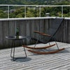 屋外デッキにブラックのロッキングチェアとテーブルが設置された画像です。本商品にはテーブル、小物は付属していません。