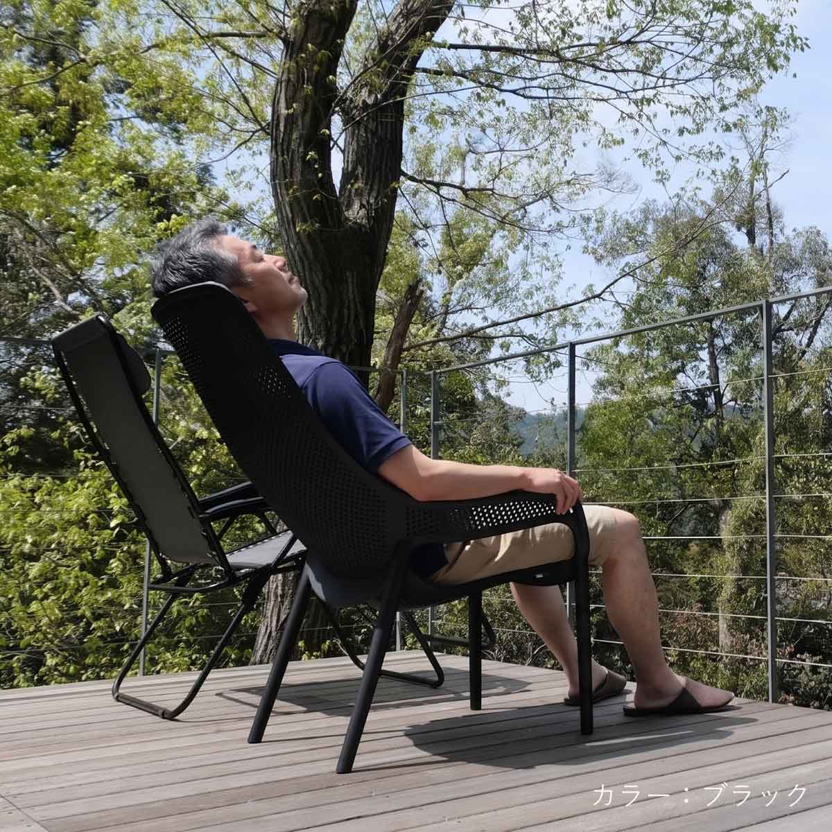 ウッドデッキの上でCORY（コーリー）ハイバックチェアを使って男性が日光浴をしている使用イメージ画像。屋外の自然光の中でチェアに深く腰かけ、心地よいリラクゼーションタイムを楽しむシーンを表現しています。