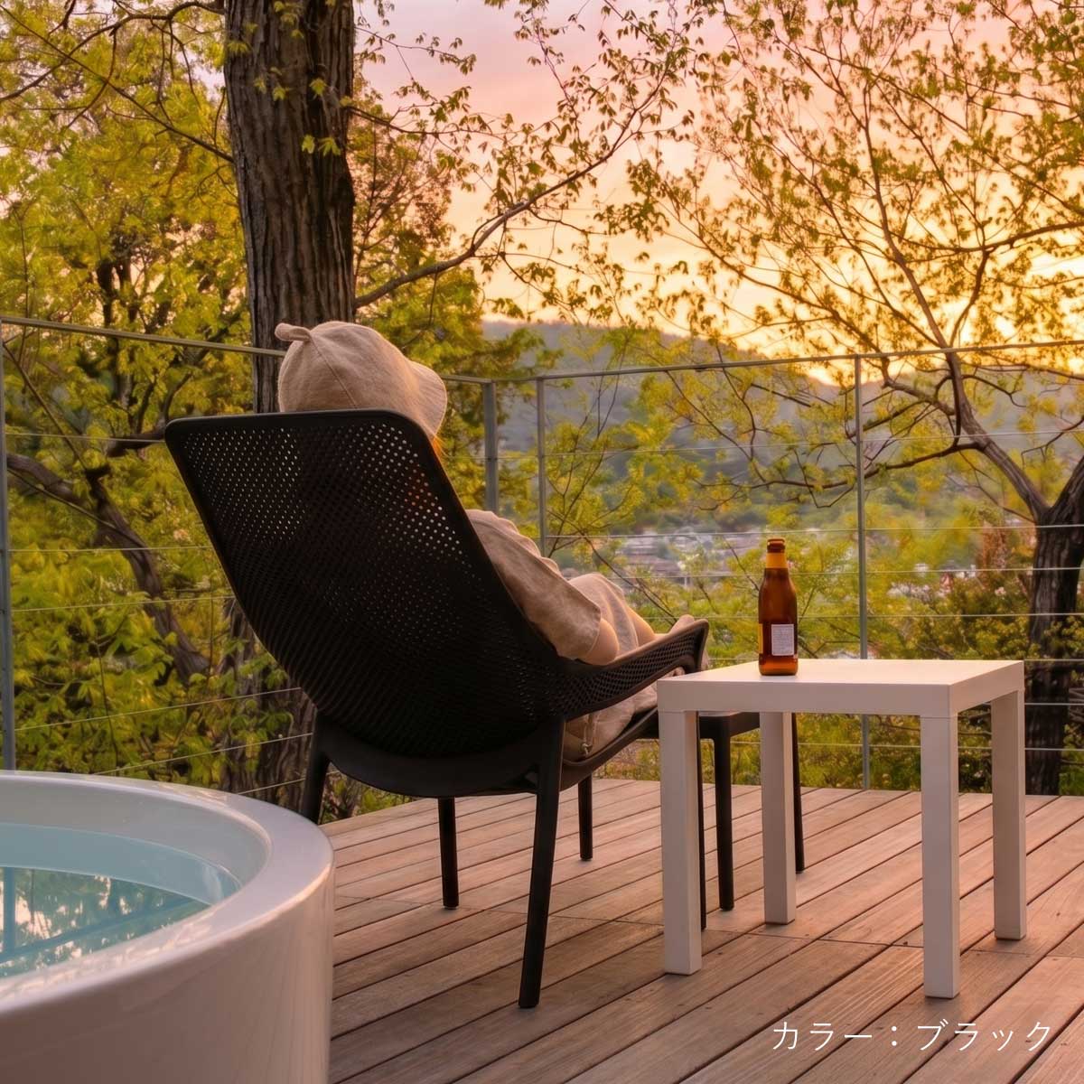 夕方のサウナ上がりに、女性がブラックカラーの「CORYハイバックチェア」とオットマンにゆったりと座ってくつろいでいる使用イメージ画像です。