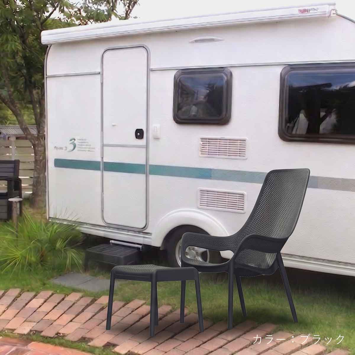 キャンピングカーの横にブラックのCORYハイバックチェアとオットマンが置かれた使用イメージ画像。アウトドアシーンにも映えるスタイリッシュなデザインで、グランピングやキャンプでの特別なひとときを演出します。