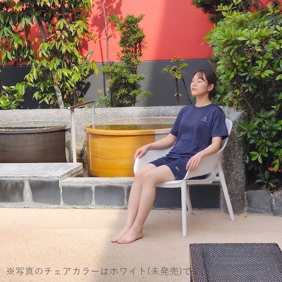 サウナの水風呂の横で女性がコーリー アームチェアに座り、外気浴を楽しんでいる設置イメージ画像。
